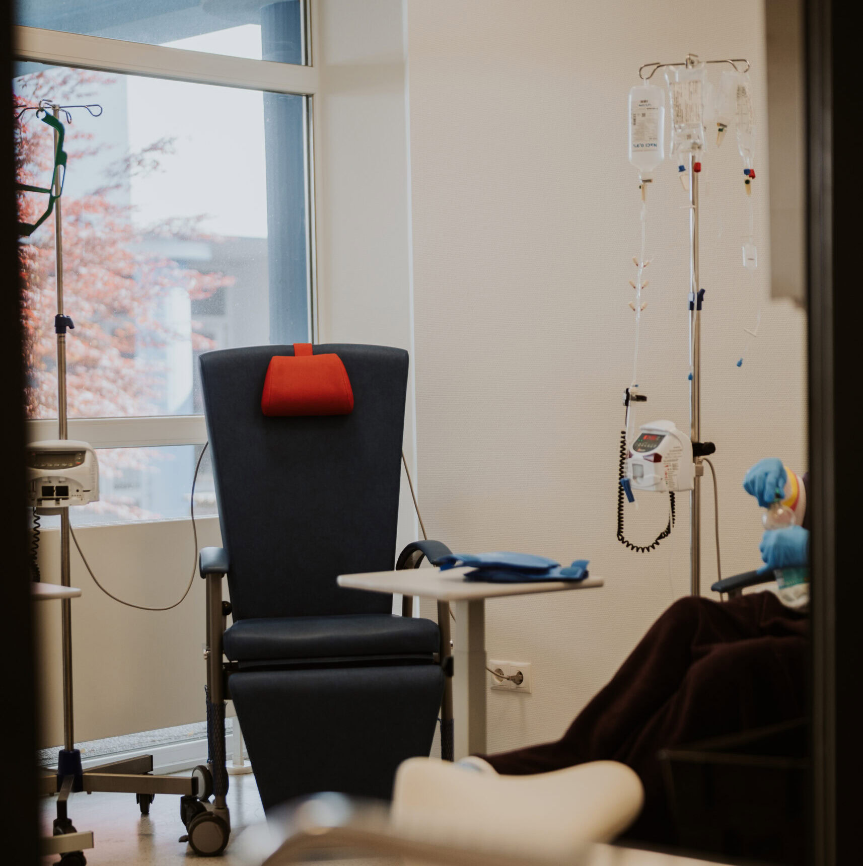 Helles Behandlungszimmer mit Thronstuhl, Infusionsständer und medizinischer Ausstattung.